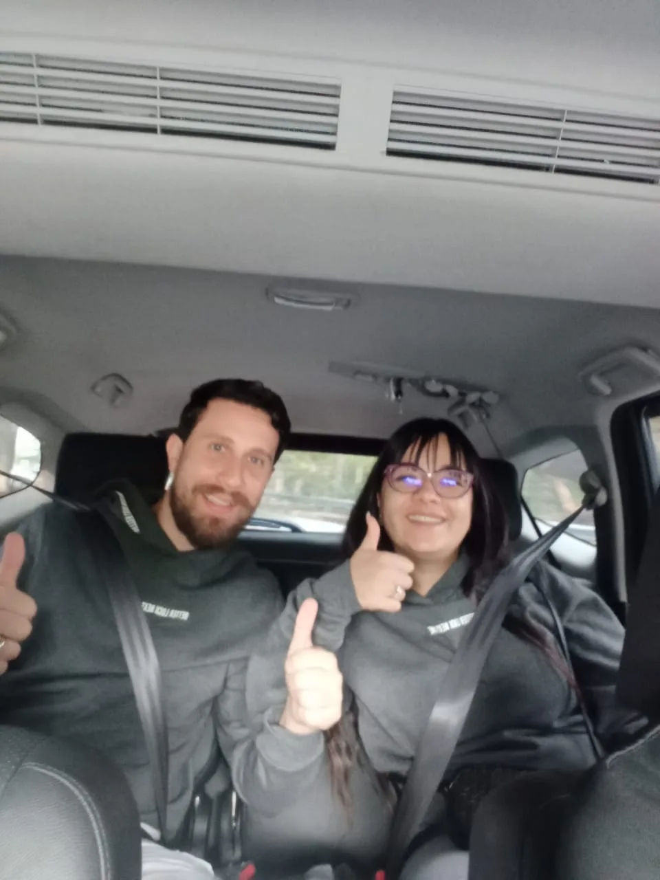 Happy couple giving thumbs up in vehicle