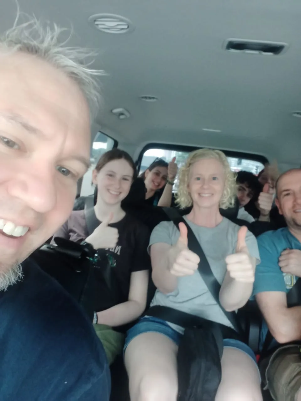 Large family group giving thumbs up in spacious van