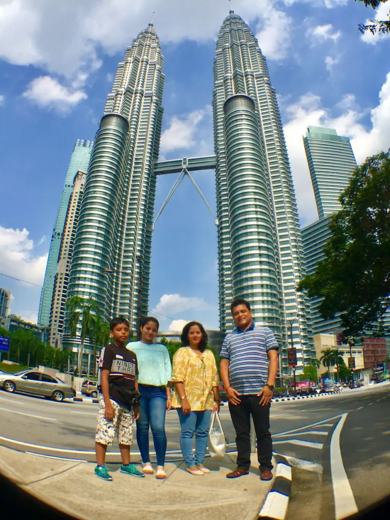 Family posing with Petronas Twin Towers in Kuala Lumpur