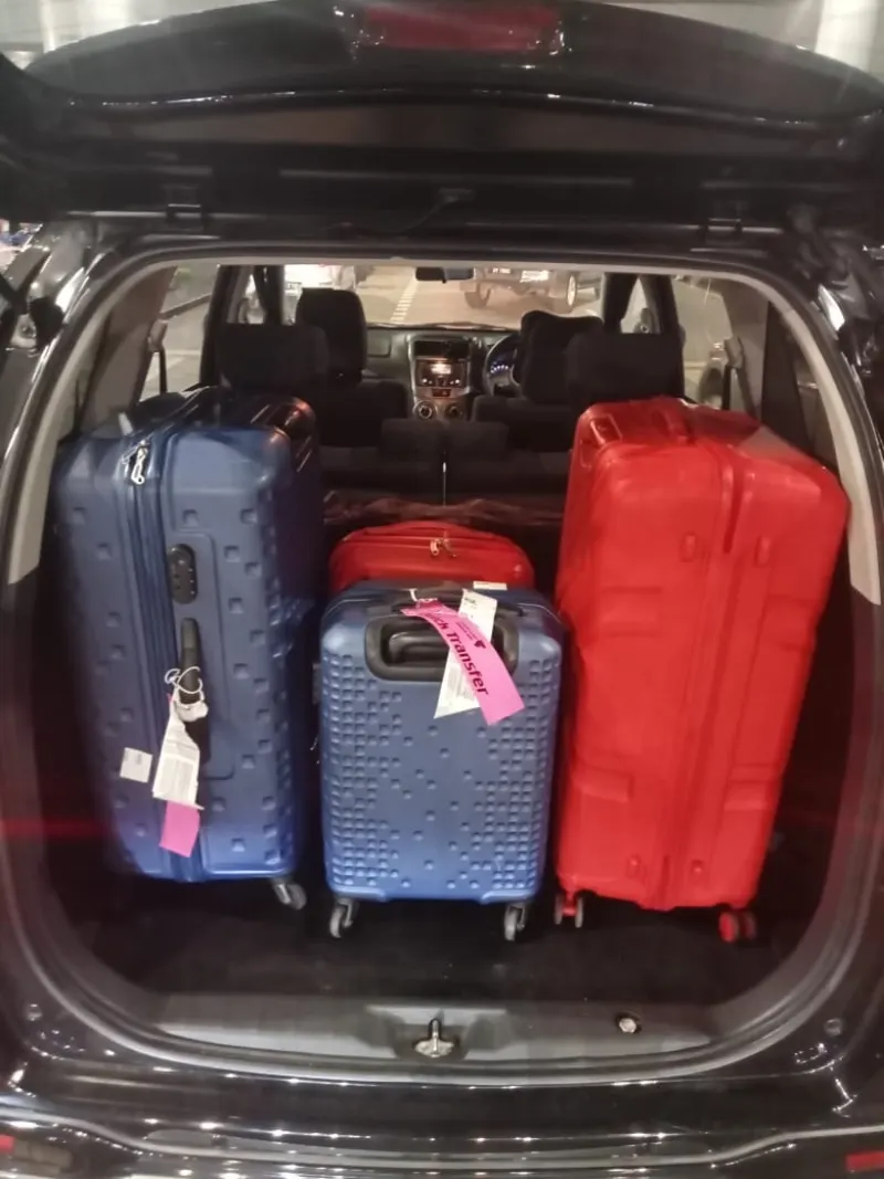 Four large suitcases neatly packed in MPV boot for airport transfer