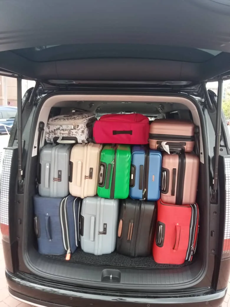 Van boot packed with twelve colourful suitcases for group transfer