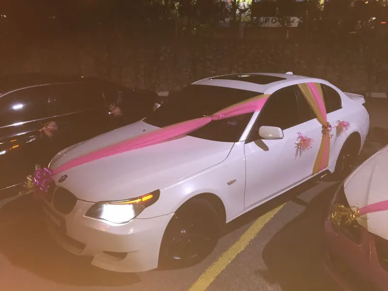 White BMW with pink and gold sash wedding decoration closeup